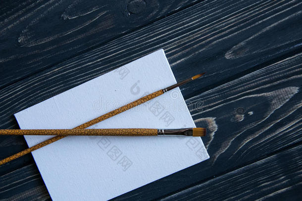 艺术和工艺工具。艺术家的画笔、画布、深色乡村背景上的调色刀