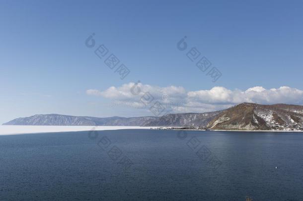 贝加尔湖春景观。 白雪覆盖的湖岸。 岩石森林海岸线。 冰和开放的边界