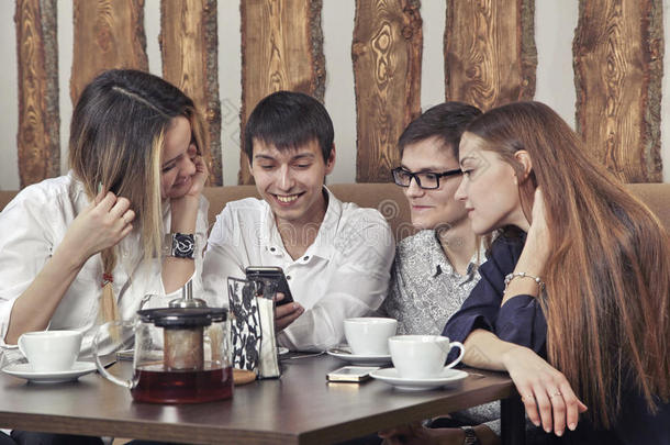 一群来自两对男孩和女孩的年轻人在咖啡馆里喝茶，全神贯注地看着智能手机
