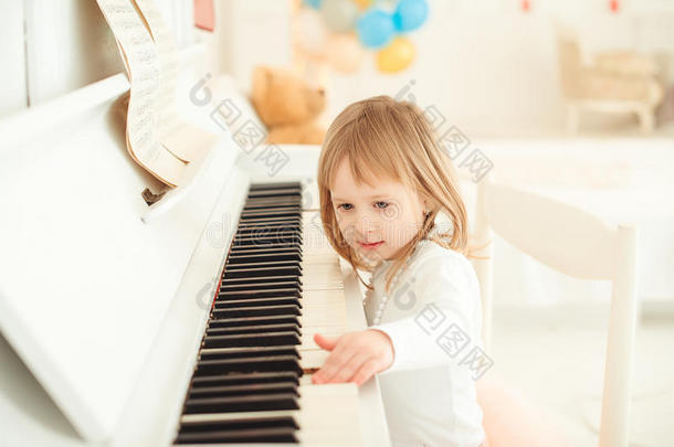 可爱的小女孩在灯光室弹钢琴。