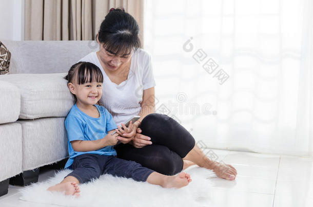 亚洲的中国母女在地板上使用智能手机