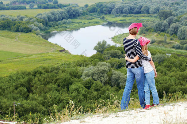 大人和孩子站在河边的山顶上。