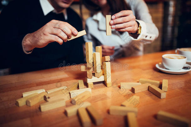 在咖啡店，手放在桌子上折叠拼图。 在桌子上玩Jenga，木托，夫妇玩