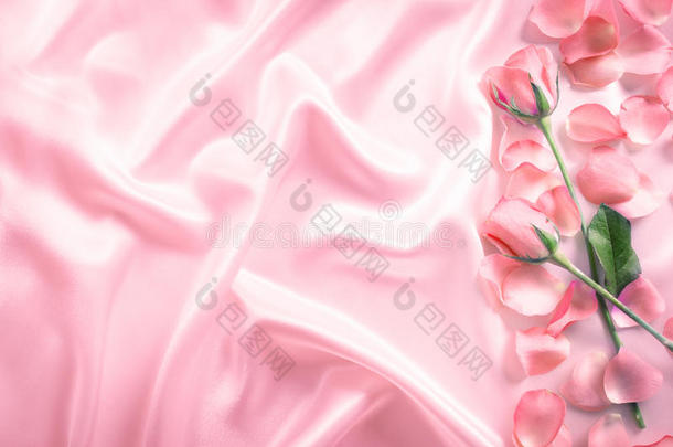 一束甜美的粉红色玫瑰花瓣在柔软的粉红色丝绸织物上