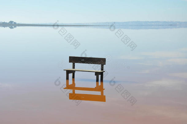 站在水中央的一张空长凳。 晴天。 平静的水。