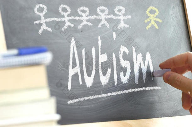 在课堂上用手写在黑板上，上面写着自闭症这个词。