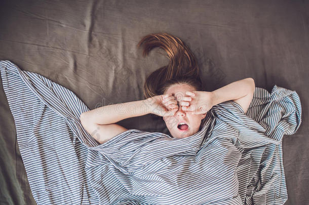 美丽的年轻女人躺在床上睡觉，俯视图。 没有足够的睡眠概念