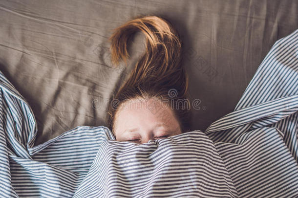 美丽的年轻女人躺在床上睡觉，俯视图。 没有足够的睡眠概念