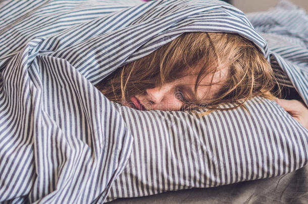 美丽的年轻女人躺在床上睡觉。 没有足够的睡眠概念