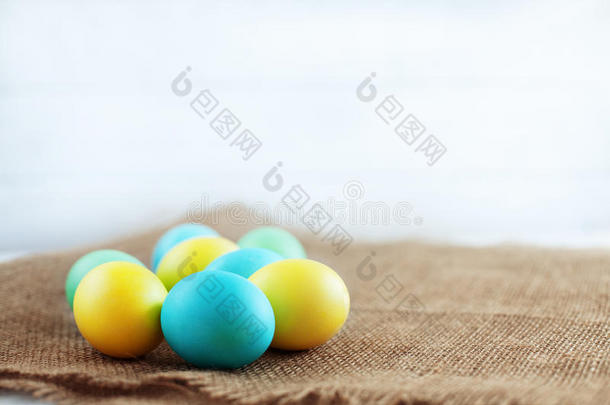 彩色鸡蛋躺在麻袋上。 快乐复活节的概念