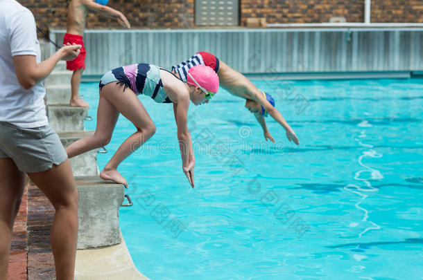 女指导员监测儿童在游泳池潜水的时间