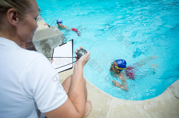 女指导员监测游泳池儿童游泳时间