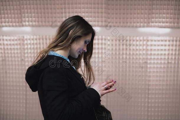 黑发女人站在地铁平台上使用智能手机。 女孩在等火车时上网。