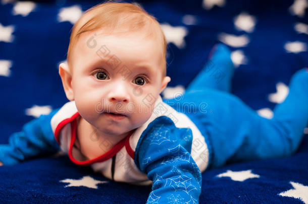 孩子6个月大，在星空的蓝色毯子上在家里微笑