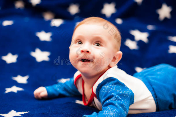孩子6个月大，在<strong>星空</strong>的<strong>蓝色</strong>毯子上在家里微笑