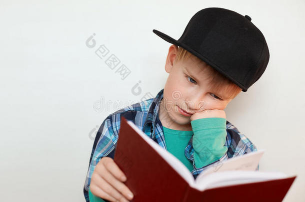 一张年轻的小学生辛勤工作的照片，他坐在那里，手放在脸颊上，读着一本书，为新材料做准备