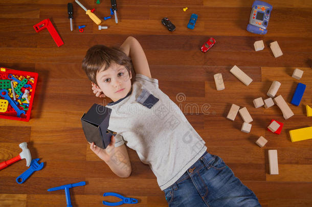 儿童与三维虚拟现实，虚拟现实纸板眼镜躺在木地板上。他身边有很多玩具