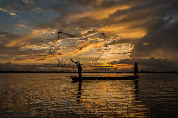 渔夫正在河边用渔网钓鱼。