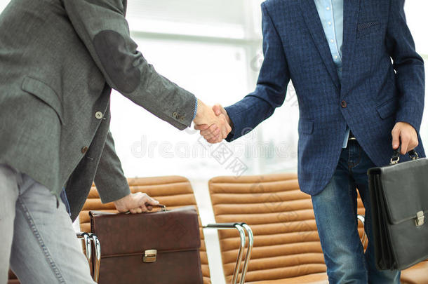 <strong>公司员工</strong>拿着公文包在现代办公室的大厅里握手