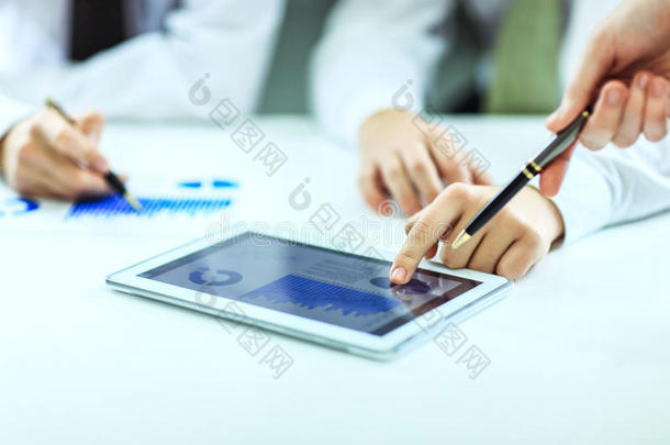 商人使用数字平板电脑，与财务时间表在办公桌上工作