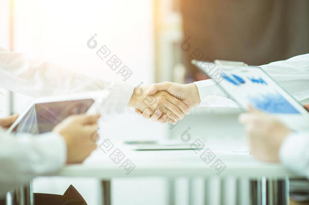 握手经理和客户在明亮的办公室背景。照片有一个空的空间为您的文本