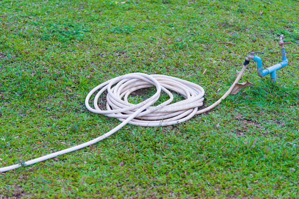 花园软管或白色橡胶管与水龙头在草地上。