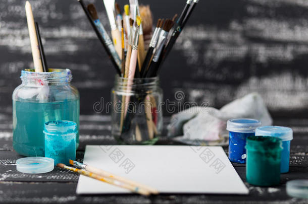 艺术家`的工作坊。 画布，油漆，刷子，调色板刀躺在桌子上。艺术工具。艺术家工作场所背景。丙烯酸油漆