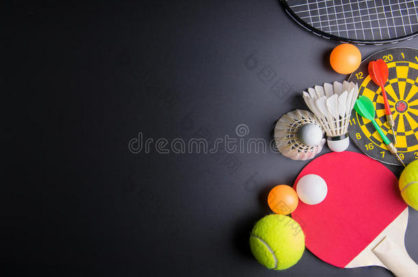 飞镖，球拍乒乓球，乒乓球，羽毛球，羽毛球拍和黑色背景的网球。运动概念，警察