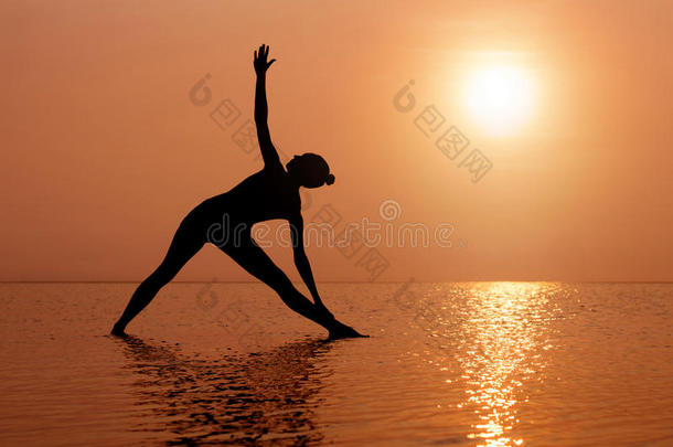 日落时在海滩上练瑜伽