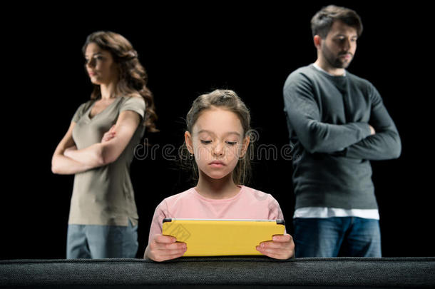 女孩使用数字平板电脑，而父母站在黑色交叉手臂