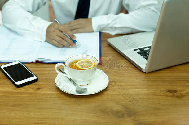 女商人手拿笔，拿着一杯柠檬茶，笔记本电脑和手机