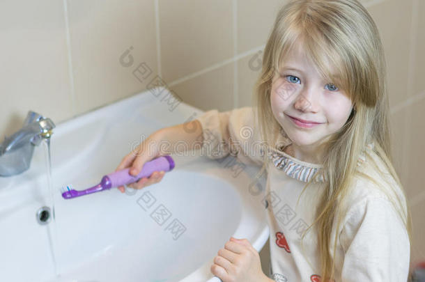浴室里的一个小女孩洗了一把<strong>电动牙刷</strong>。