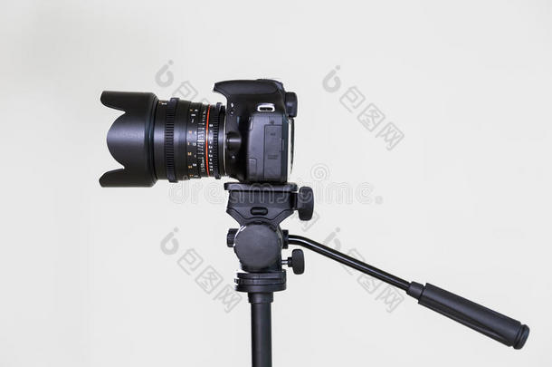 数字SLR相机在三脚架上，可移动的手动镜头在灰色背景上。 在内部射击