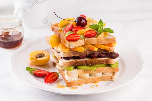 充满新鲜热带水果切片、草莓和樱桃的创意健康汉堡。 健康的饮食观念