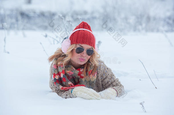 戴着红色帽子的漂亮女孩，戴着耳机和围巾，穿着粉红色的雪中毛衣