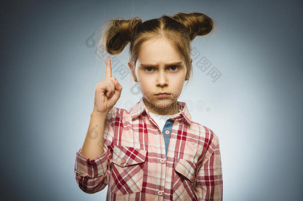 不高兴和轻蔑的女孩威胁手指在灰色的背景