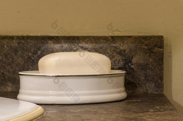 坐在深色脸盆上的盘子里的白色肥皂棒