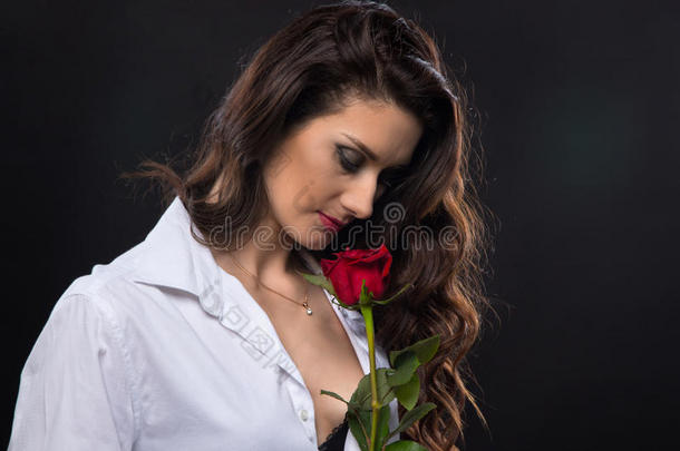 黑发卷曲的女人拿着红玫瑰