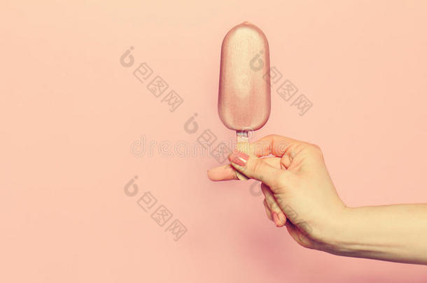 粉红色背景上拿着冰淇淋的年轻女人的手。时尚背景。<strong>夏季</strong>概念。调色。