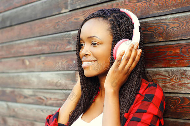 时尚肖像快乐微笑的非洲女人戴着耳机正在享受听背景音乐