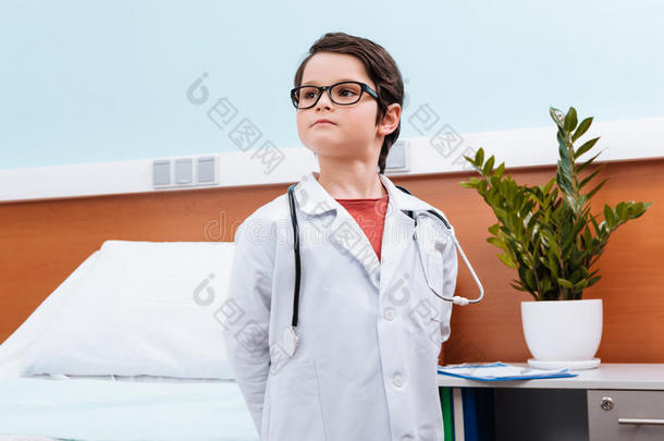 穿着医疗制服的男孩医生在医院的房间里看着