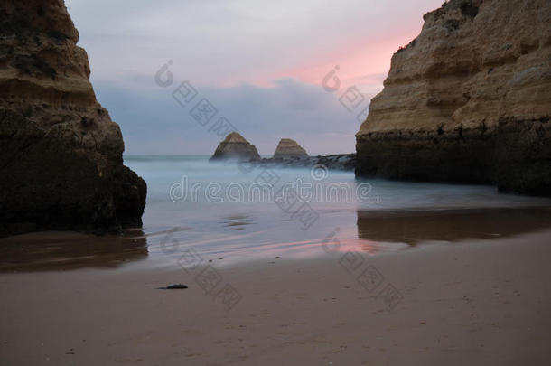 美丽雄伟的悬崖在丝绸缎子软海洋在沙滩上的红色日落