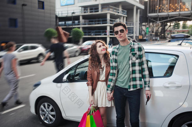 漂亮的年轻夫妇站在一辆车附近，购物
