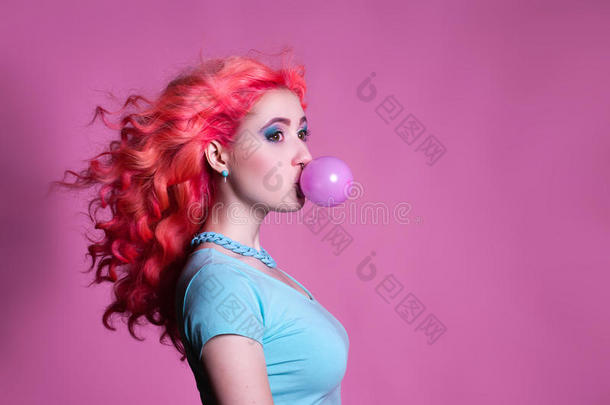 粉红色背景上有粉红色头发的女孩嚼口香糖