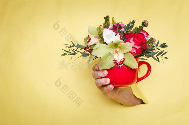 手拿着小花瓶，花和百合通过黄色的背景盈亏平衡