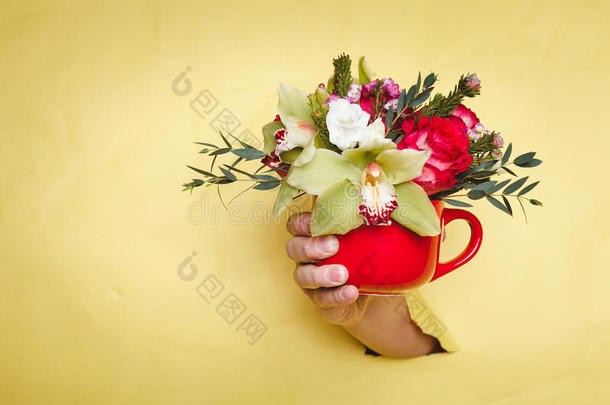 手拿着小花瓶，花和百合通过黄色的背景盈亏平衡