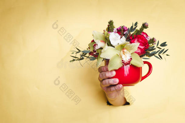 手拿着小花瓶，花和百合通过黄色的背景盈亏平衡