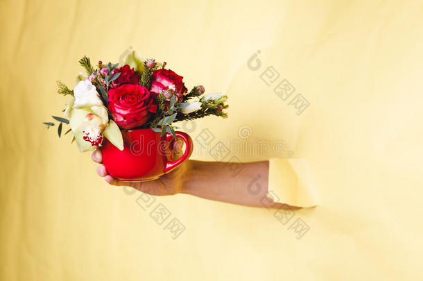 手拿着带<strong>花的小花</strong>瓶，玫瑰在<strong>黄色的</strong>背景下折断