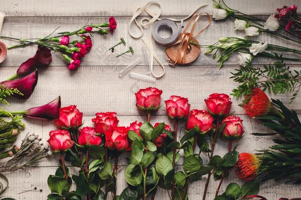 鲜花店木制桌子上的康乃馨，红玫瑰，紫色的愈伤组织
