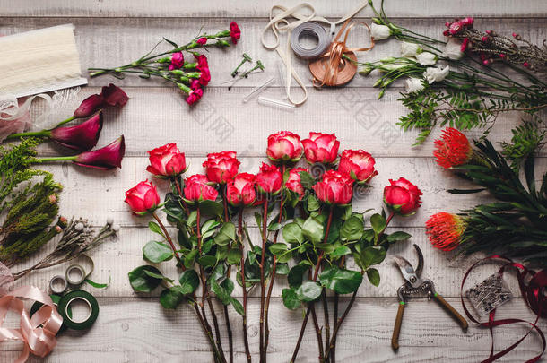 鲜花店木制桌子上的康乃馨，红玫瑰，紫色的愈伤组织